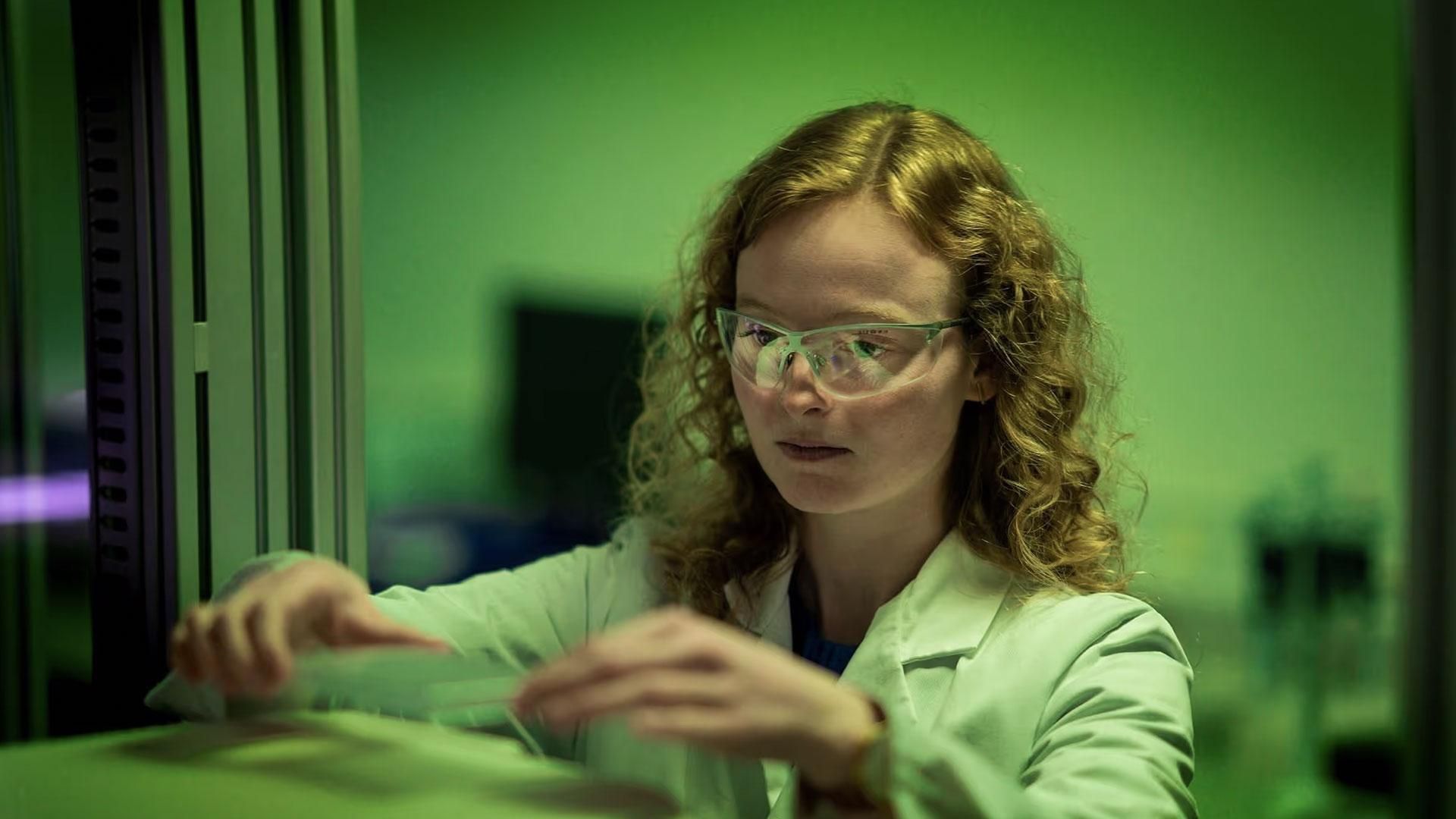 Camille De Craene, scientifique chez Sanofi, en train de faire une manipulation en laboratoire avec des lunettes de protection.  